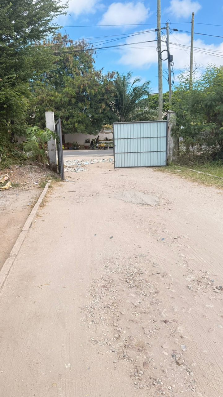 The current metal swing gate at the SBT Apartments entrance on a dusty sand driveway